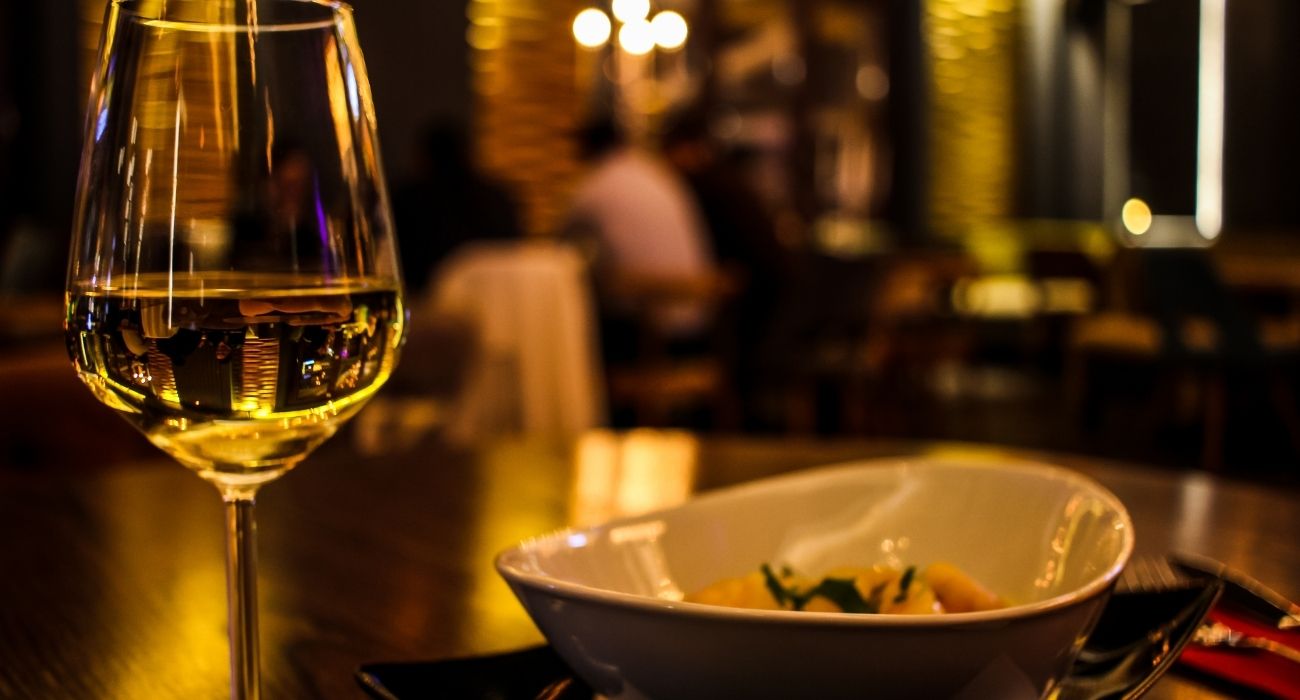 glass of winde and plated food on restaurant table